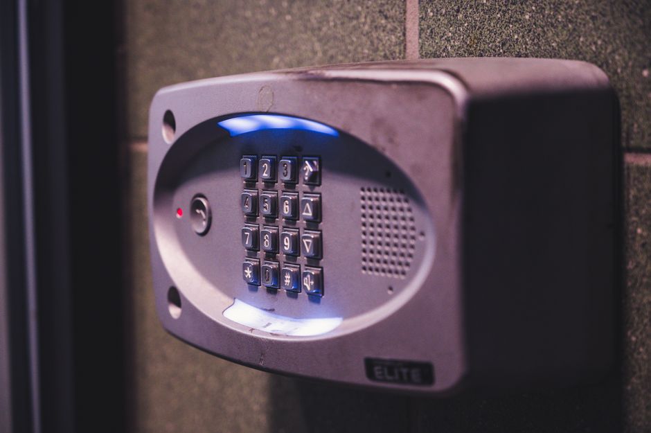 Cibersegurança Corporativa — A close-up image of an illuminated security keypad mounted on a wall.