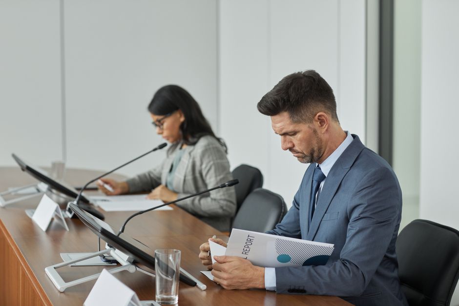 Cibersegurança Corporativa — Business professionals in a conference setting, focusing on documents and reports.